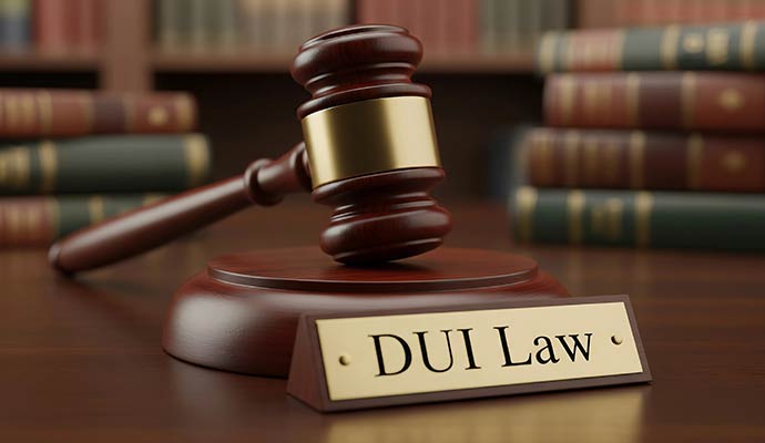 A wooden gavel resting on its sound block next to a gold plate inscribed with DUI Law on a wooden table