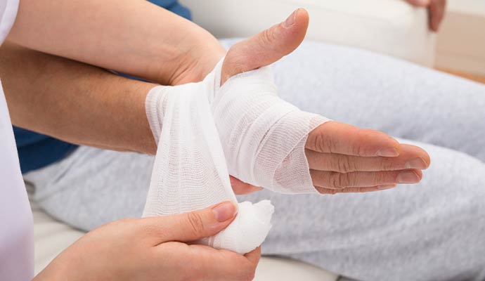 A close-up of a person's hand and wrist being wrapped in a white gauze bandage