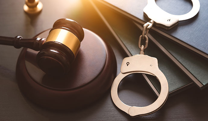 Gavel and handcuffs placed on law books representing criminal law