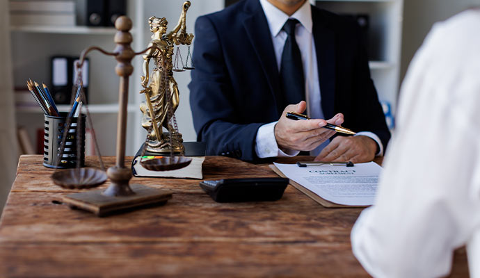 Lawyer discussing legal documents with a client at a desk with scales of justice