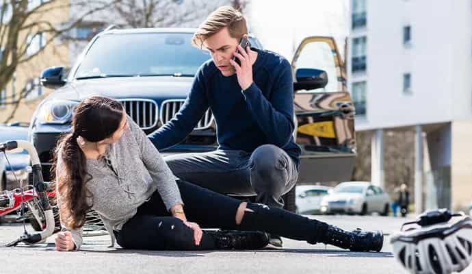 Man calling for help while assisting an injured woman after a bicycle accident