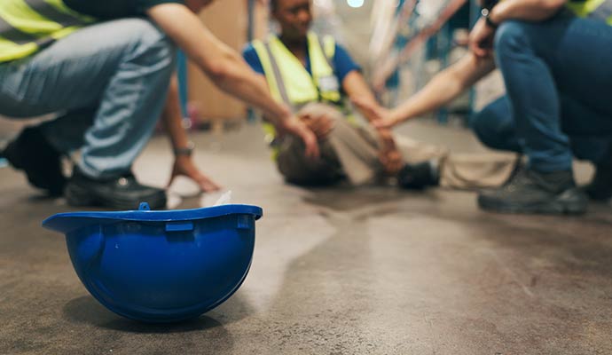 Two colleagues kneel down to help an injured worker